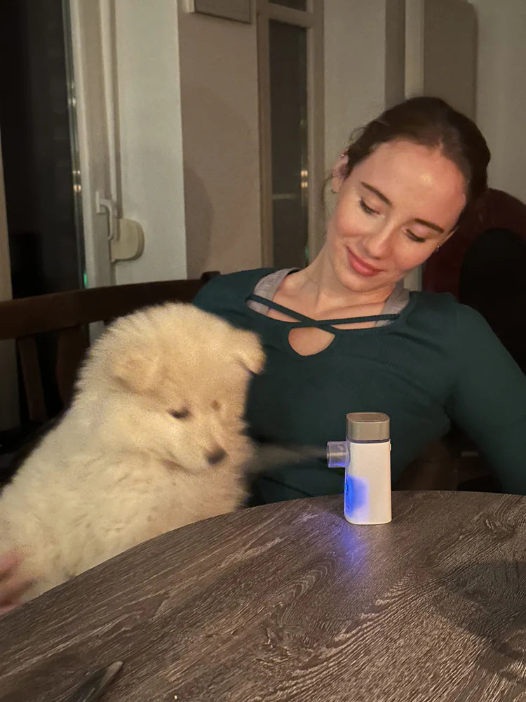 Ein Hund sitzt bei einer Frau auf dem Schoß und inhaliert Salzsole mit dem Medel Taschenvernebler