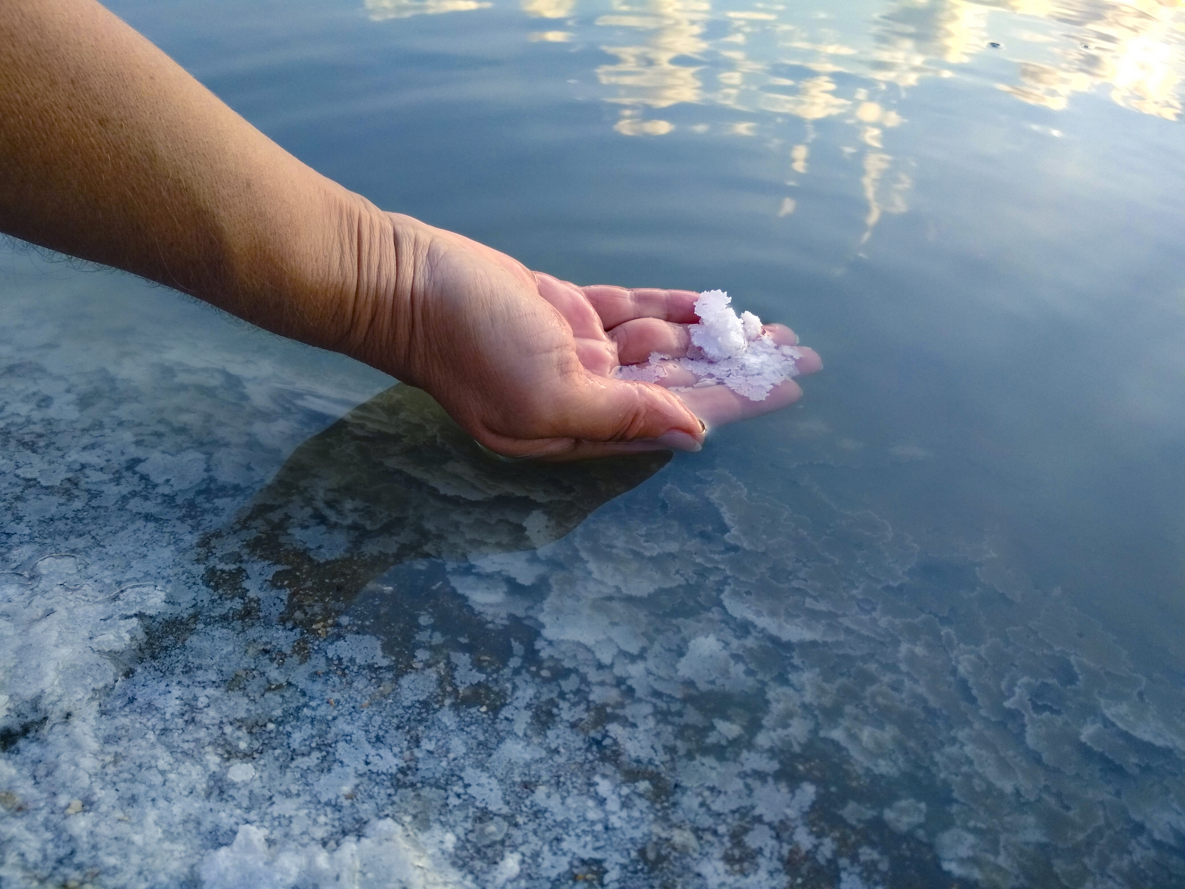 Eine Hand schöpft Salz aus einem See